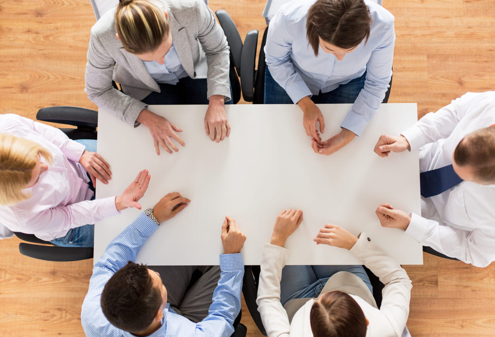 People seated around a rectangular table, viewed from above, engaged in a discussion.