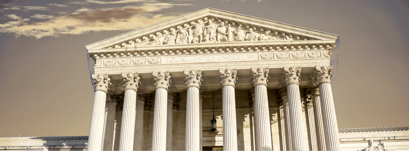 The image shows the front facade of a neoclassical building with eight columns and intricate carvings on the pediment.