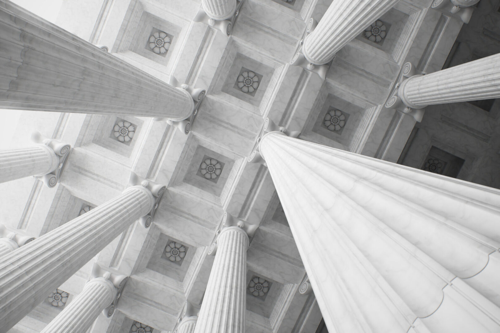 Upward view of tall, white, marble columns supporting an ornate, coffered ceiling with geometric patterns.